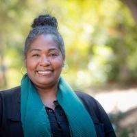 Wendy Jackson outside at Westmont smiling wearing a blue scarf and black shirt with her hair in a bun